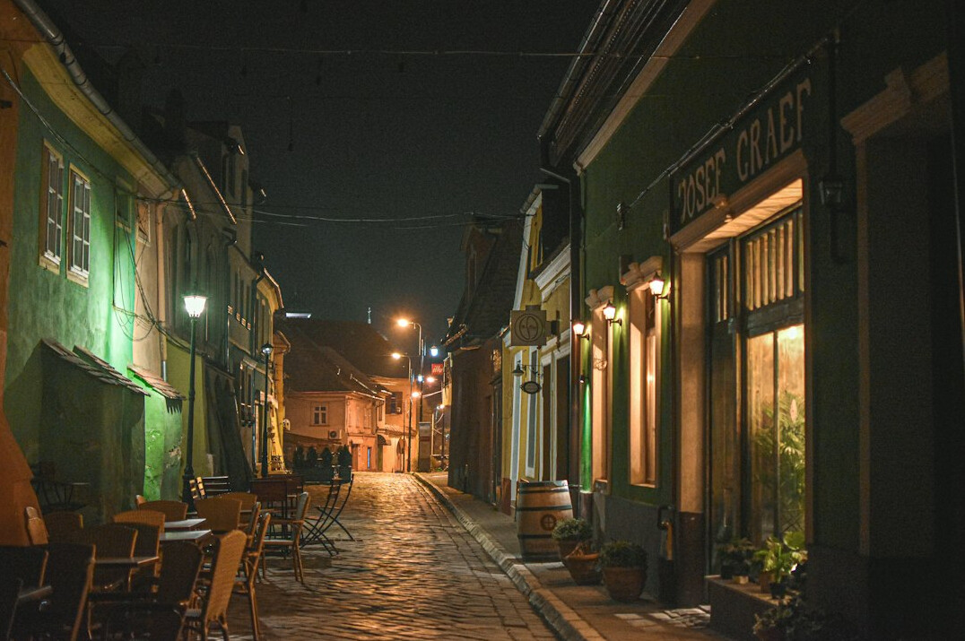 Old city street at dusk with warm lights and fog